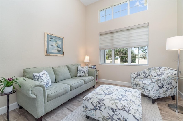 living room with baseboards, a high ceiling, and wood finished floors