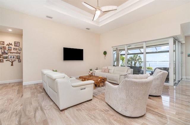 living area with baseboards, visible vents, a high ceiling, ceiling fan, and a raised ceiling