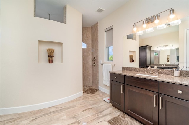 full bathroom featuring visible vents, baseboards, walk in shower, wood finished floors, and vanity