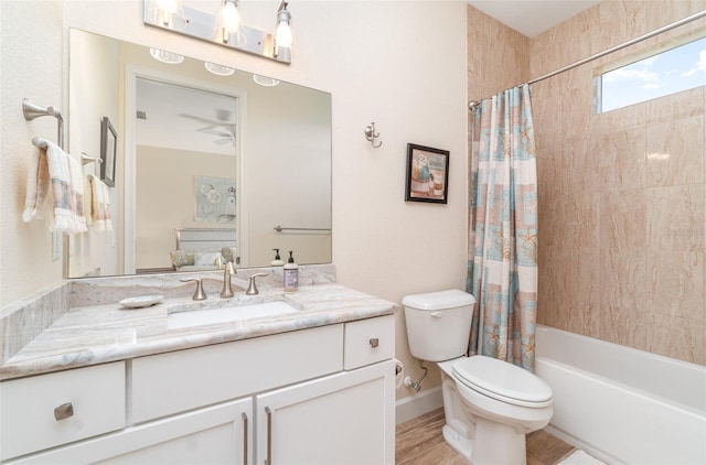 ensuite bathroom with toilet, a ceiling fan, shower / bath combination with curtain, baseboards, and vanity