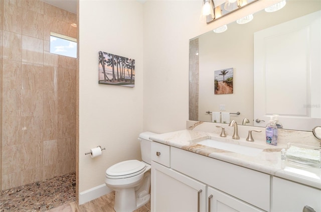 full bathroom featuring vanity, toilet, a walk in shower, and baseboards