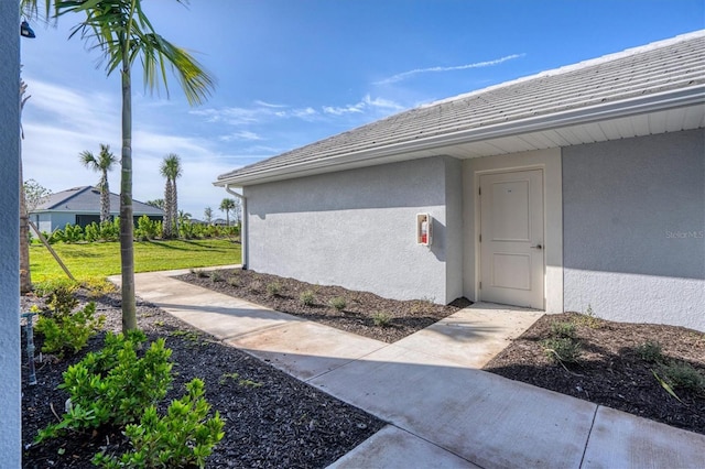 exterior space with a lawn, a tile roof, and stucco siding