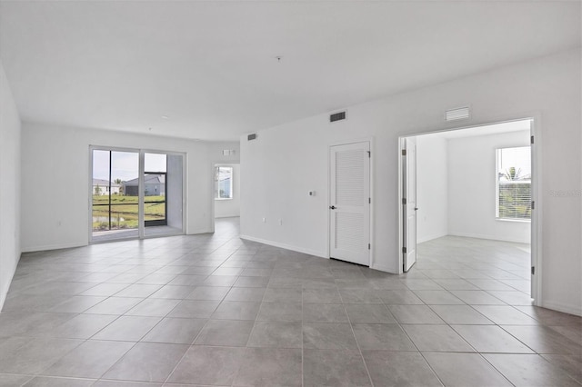 unfurnished room with light tile patterned floors, visible vents, and a wealth of natural light