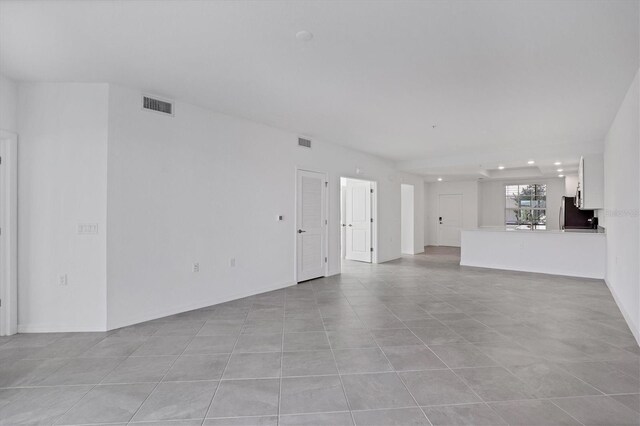 unfurnished living room with light tile patterned floors, visible vents, and baseboards