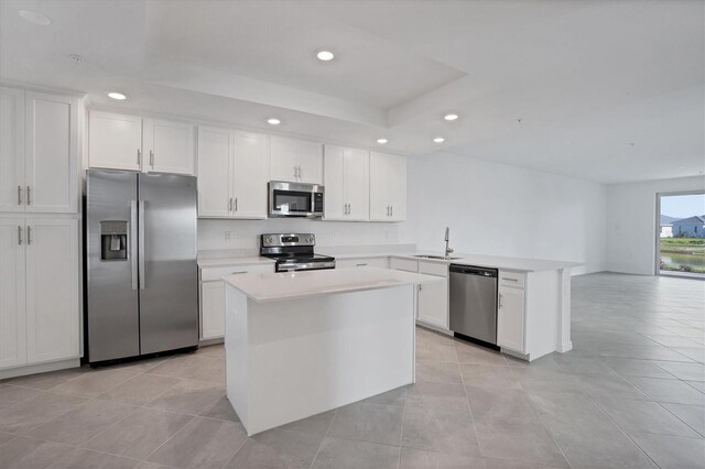 kitchen featuring a peninsula, light countertops, stainless steel appliances, a sink, and recessed lighting