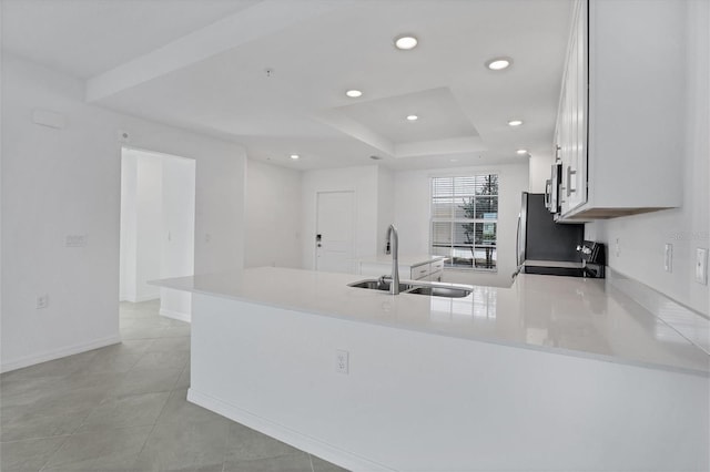 kitchen with recessed lighting, light countertops, a sink, range with electric cooktop, and a peninsula