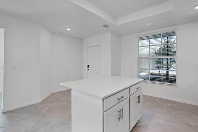 kitchen featuring light countertops, visible vents, white cabinetry, a kitchen island, and baseboards