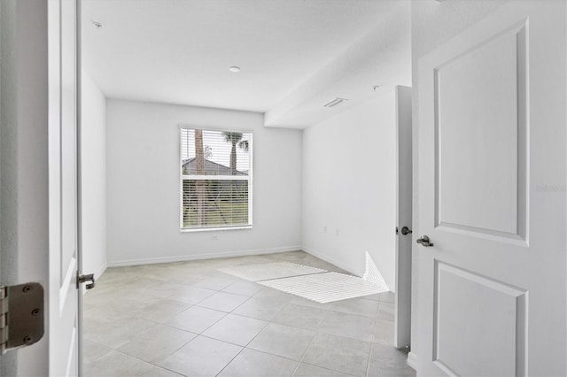 spare room featuring light tile patterned floors, visible vents, and baseboards