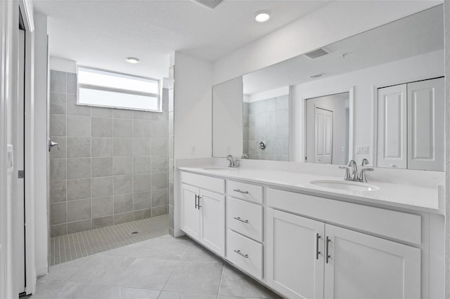 bathroom featuring tile patterned flooring, double vanity, a sink, and a walk in shower