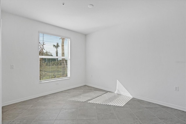 unfurnished room with tile patterned floors and baseboards