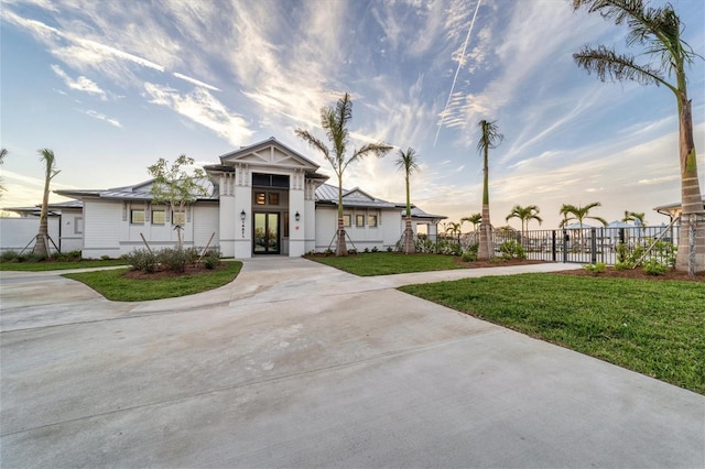 view of front facade featuring fence, driveway, french doors, a gate, and a front lawn