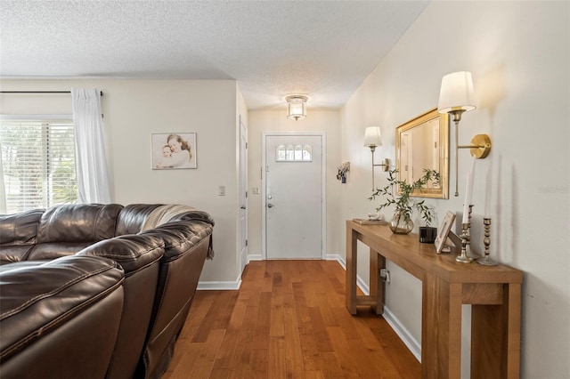 entrance foyer with a textured ceiling, baseboards, and wood finished floors