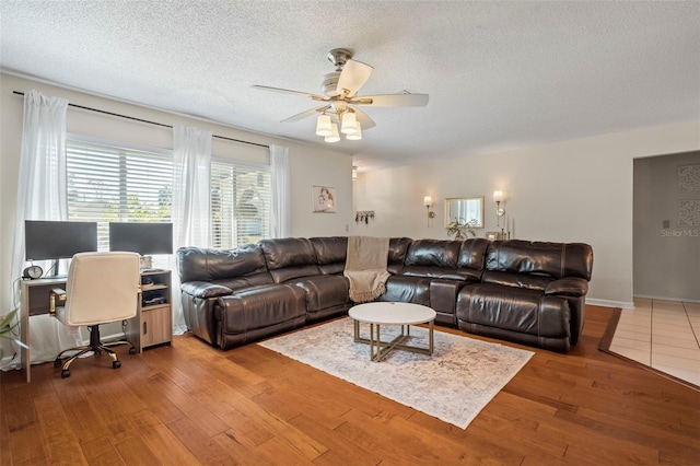 living room with a textured ceiling, wood finished floors, and a ceiling fan