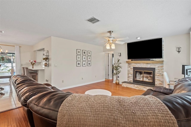 living area with visible vents, a fireplace, a textured ceiling, and wood finished floors