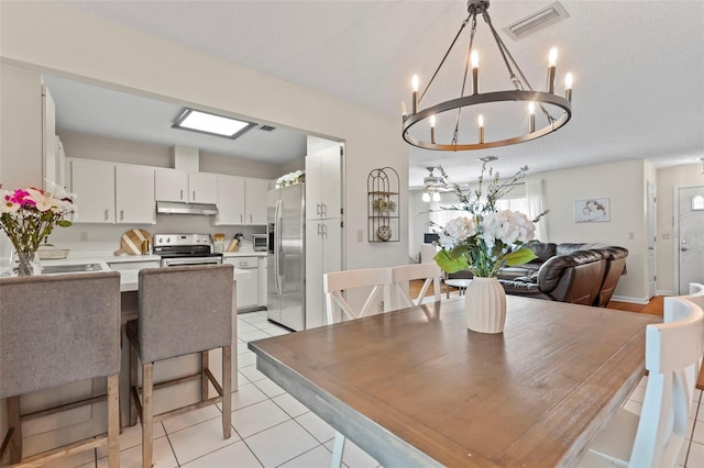 dining room with light tile patterned flooring, visible vents, and a notable chandelier