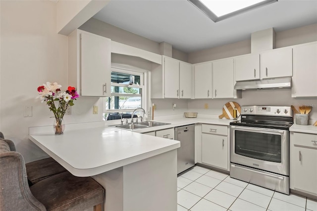 kitchen with under cabinet range hood, a sink, appliances with stainless steel finishes, a peninsula, and light countertops