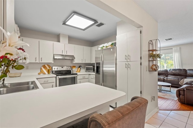 kitchen featuring visible vents, open floor plan, under cabinet range hood, and stainless steel appliances