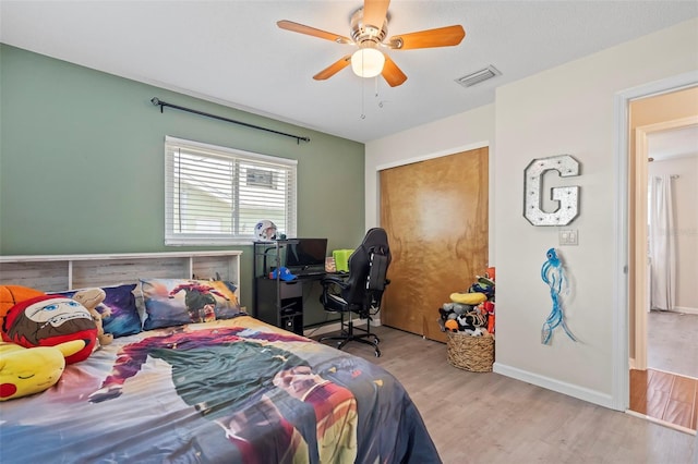 bedroom with visible vents, baseboards, wood finished floors, a closet, and a ceiling fan