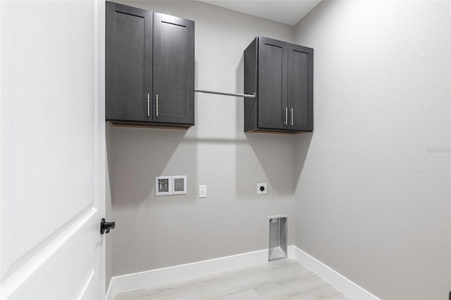 clothes washing area featuring hookup for a washing machine, cabinet space, light wood-style flooring, hookup for an electric dryer, and baseboards