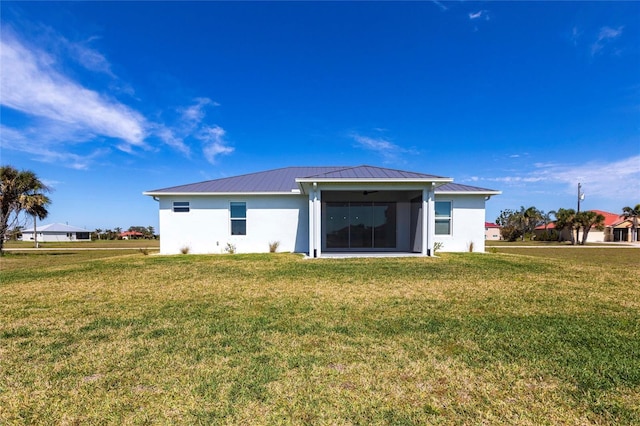 rear view of house featuring metal roof, a lawn, a standing seam roof, and stucco siding