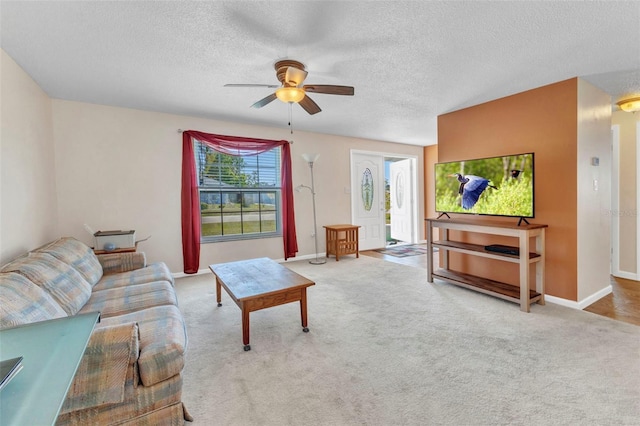 carpeted living room with a textured ceiling, baseboards, and a ceiling fan