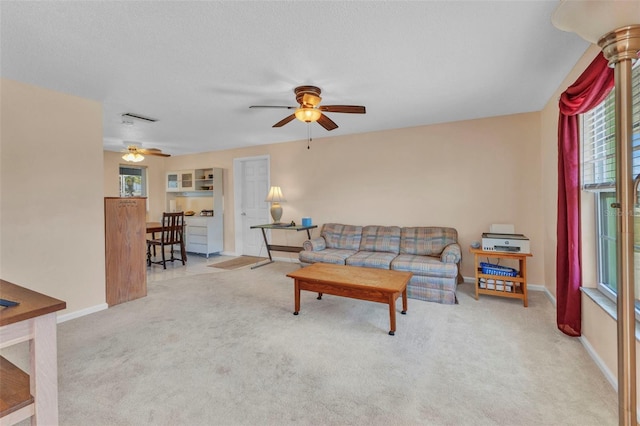 carpeted living room featuring visible vents, a textured ceiling, baseboards, and ceiling fan