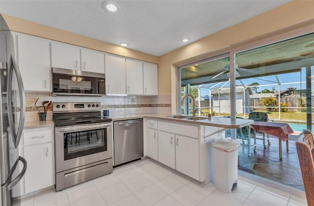 kitchen with a sink, decorative backsplash, appliances with stainless steel finishes, and white cabinets