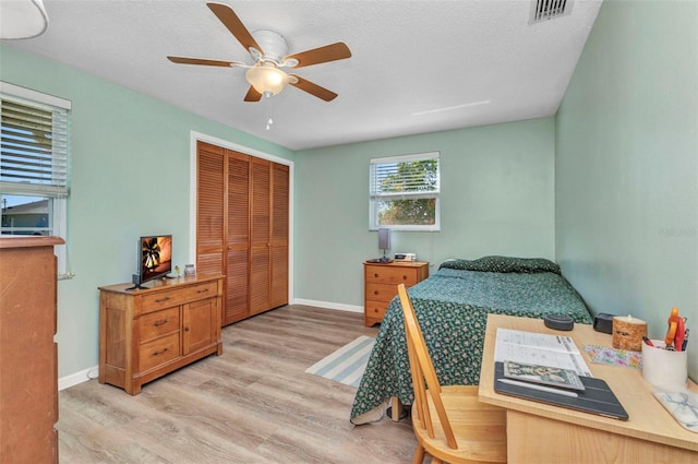 bedroom featuring visible vents, baseboards, light wood-style floors, a closet, and a textured ceiling