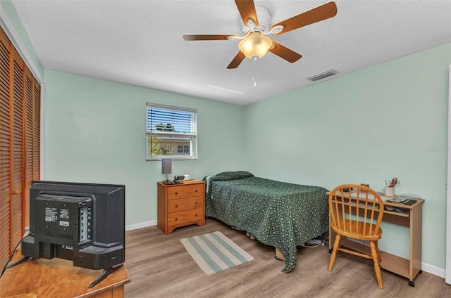 bedroom with wood finished floors, visible vents, a closet, and a textured ceiling