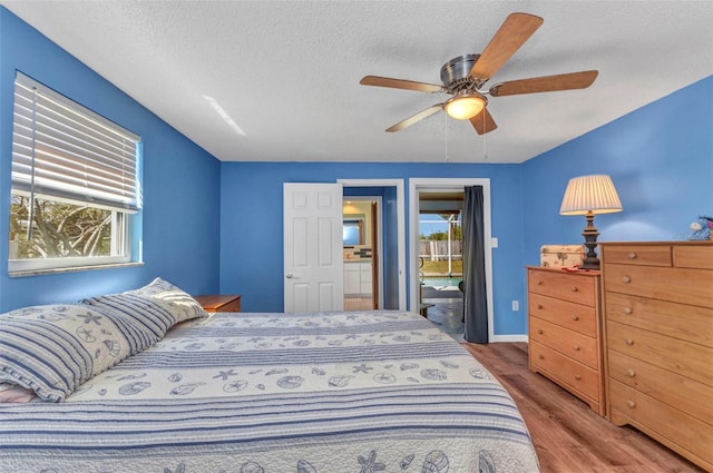 bedroom with access to outside, multiple windows, a textured ceiling, and wood finished floors