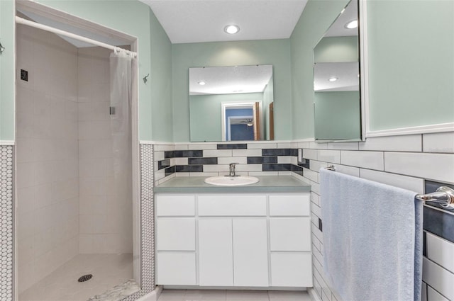 full bathroom featuring recessed lighting, vanity, tiled shower, and tile walls