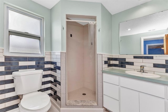 bathroom featuring toilet, tile walls, wainscoting, a shower stall, and vanity