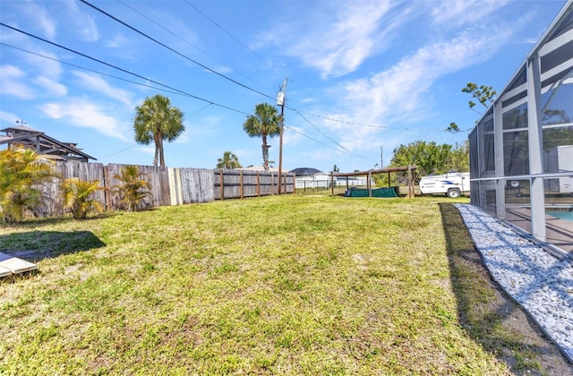 view of yard with glass enclosure and fence