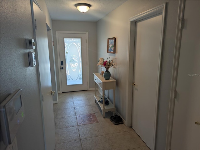 doorway to outside featuring baseboards and a textured ceiling