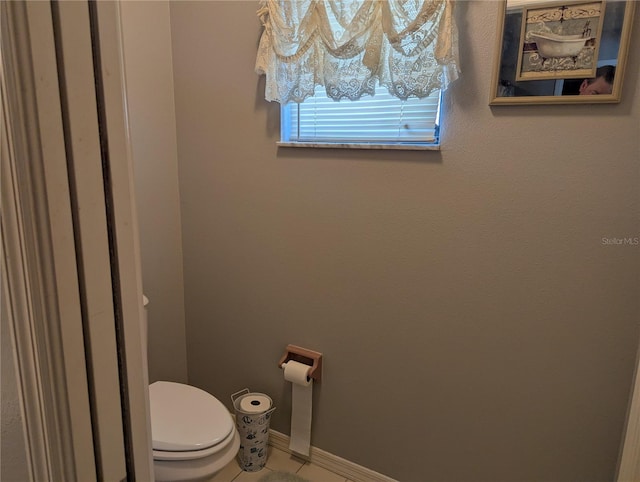 bathroom with baseboards, toilet, and tile patterned flooring