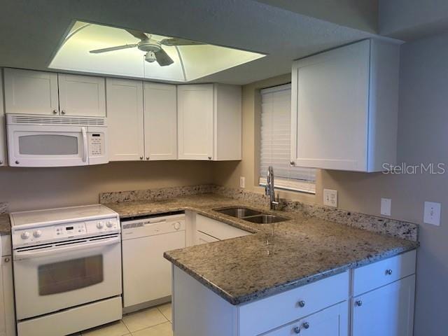 kitchen with white appliances, light tile patterned floors, a ceiling fan, stone counters, and a sink