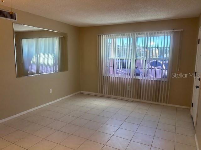 empty room featuring visible vents, plenty of natural light, and a textured ceiling