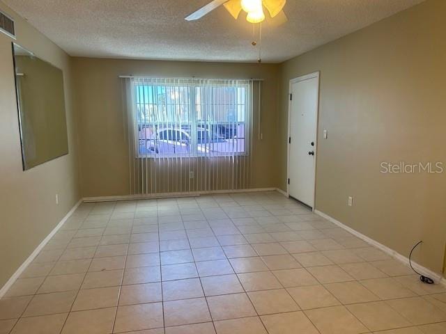 unfurnished room featuring light tile patterned floors, baseboards, and a textured ceiling