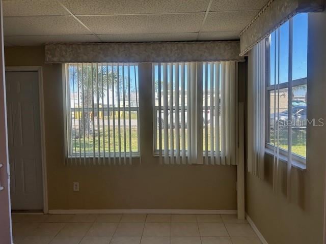 interior space with a drop ceiling, baseboards, and tile patterned flooring