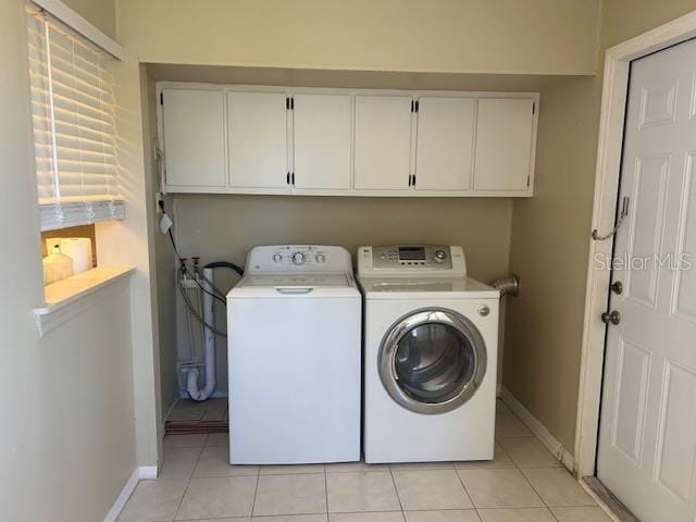 laundry room featuring cabinet space, light tile patterned floors, washer and dryer, and baseboards