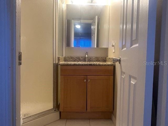 bathroom with tile patterned floors, a shower stall, and vanity