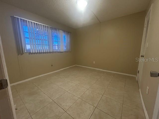 unfurnished room with light tile patterned floors, baseboards, and a textured ceiling