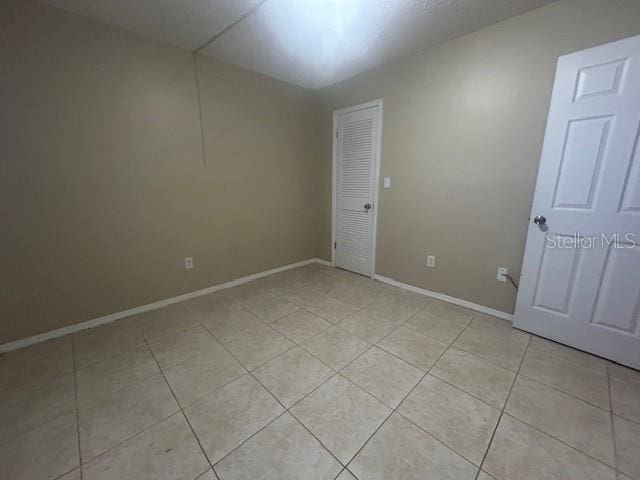 empty room featuring light tile patterned floors and baseboards