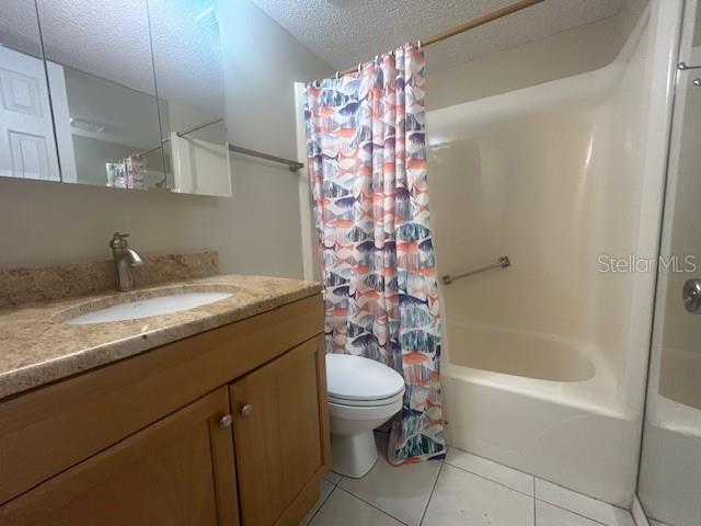 bathroom featuring shower / bathtub combination with curtain, toilet, a textured ceiling, tile patterned flooring, and vanity