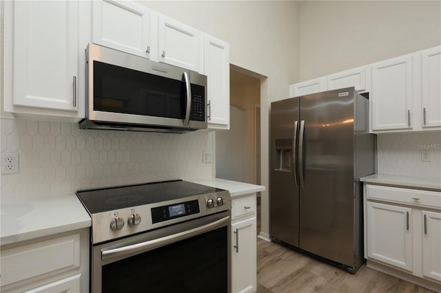 kitchen featuring decorative backsplash, light countertops, white cabinets, and stainless steel appliances