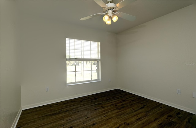 spare room featuring dark wood-type flooring, a ceiling fan, and baseboards