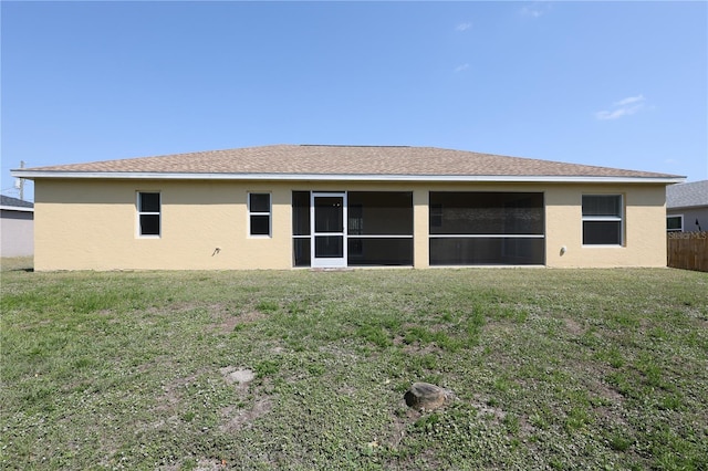 rear view of property with a yard, fence, a sunroom, and stucco siding