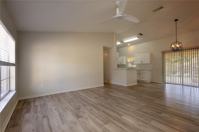 unfurnished living room featuring light wood-type flooring, visible vents, lofted ceiling, and ceiling fan with notable chandelier