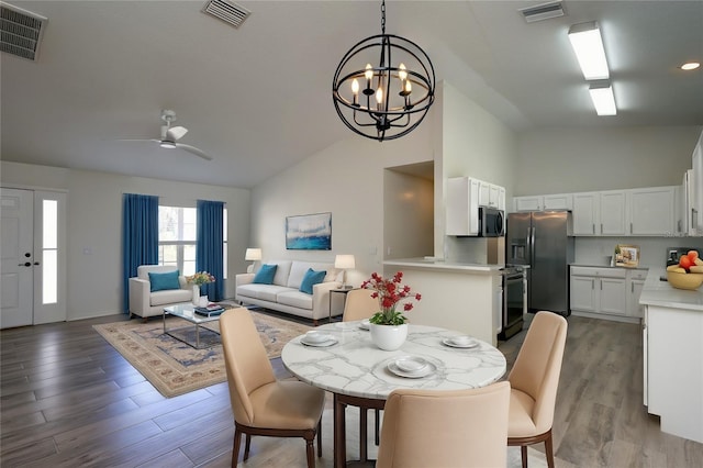 dining space with ceiling fan with notable chandelier, wood finished floors, and visible vents