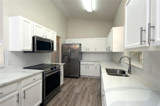 kitchen with backsplash, white cabinets, appliances with stainless steel finishes, and a sink